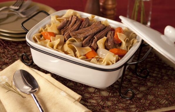 Beef pot roast and wide egg noodles with carrots and onions in a light sauce